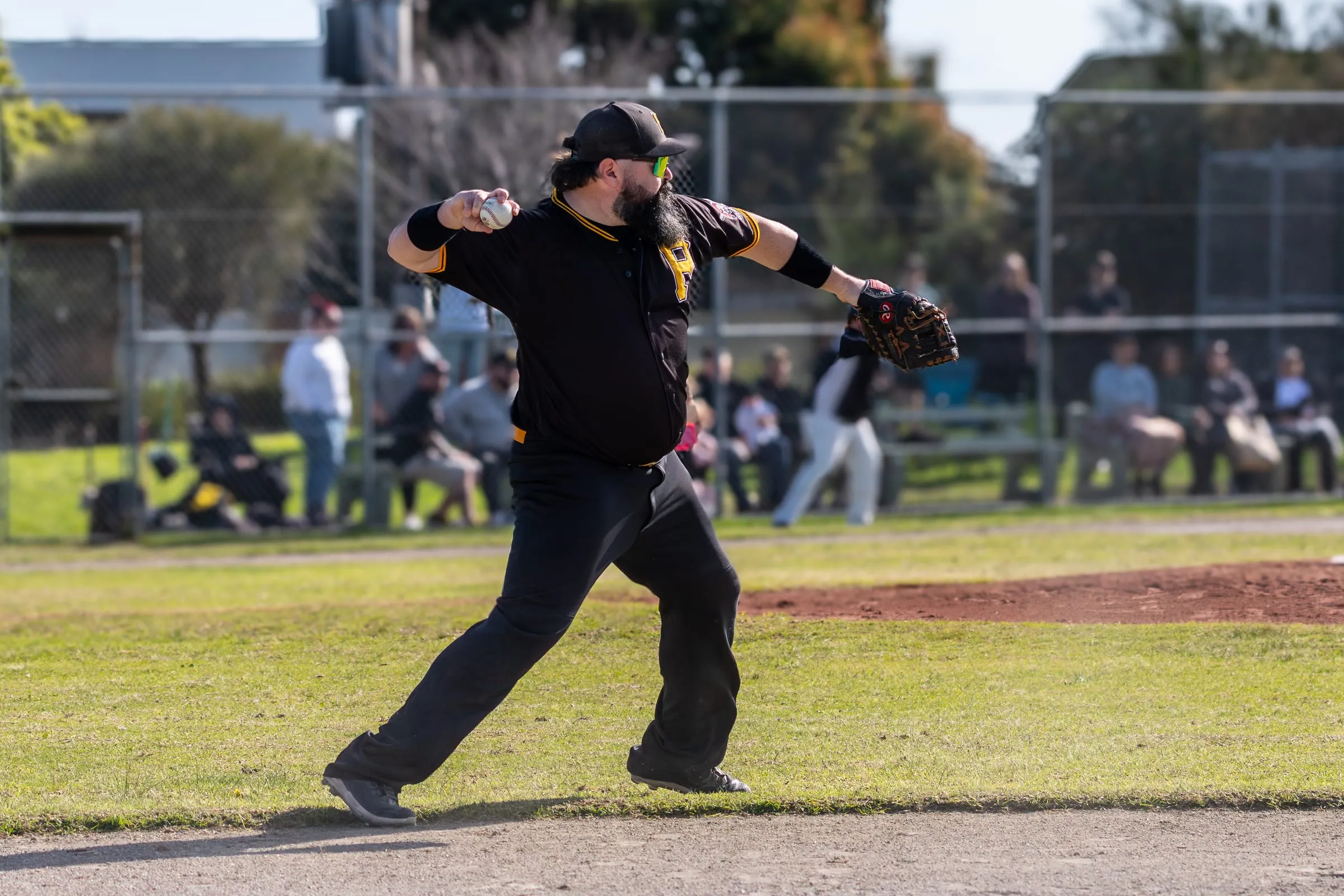 A Pirates pitcher delivers, with spectators lining the fence